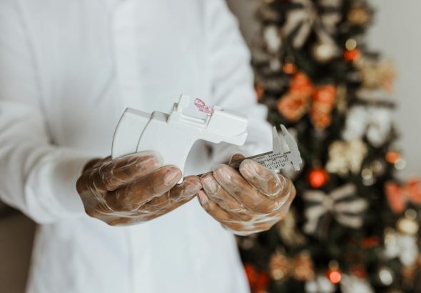 Close-up of a medical professional preparing a piercing kit indoors near a decorated Christmas tree.